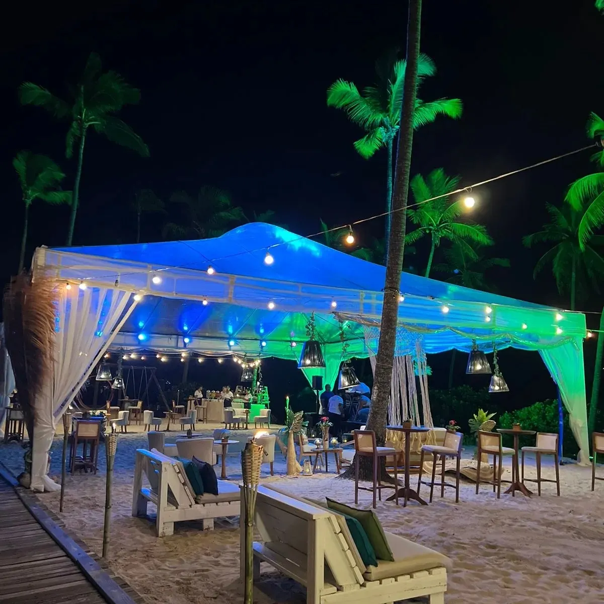 Recepção à beira-mar com iluminação azul e verde em tenda entre coqueiros