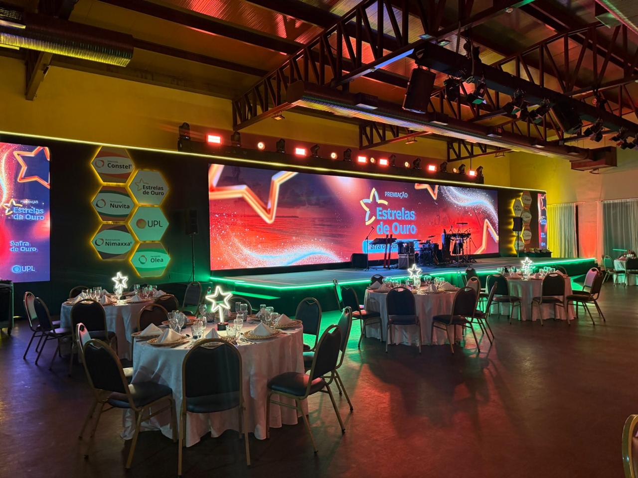 Venue completo da premiação Estrelas de Ouro com múltiplas telas e mesas elegantes